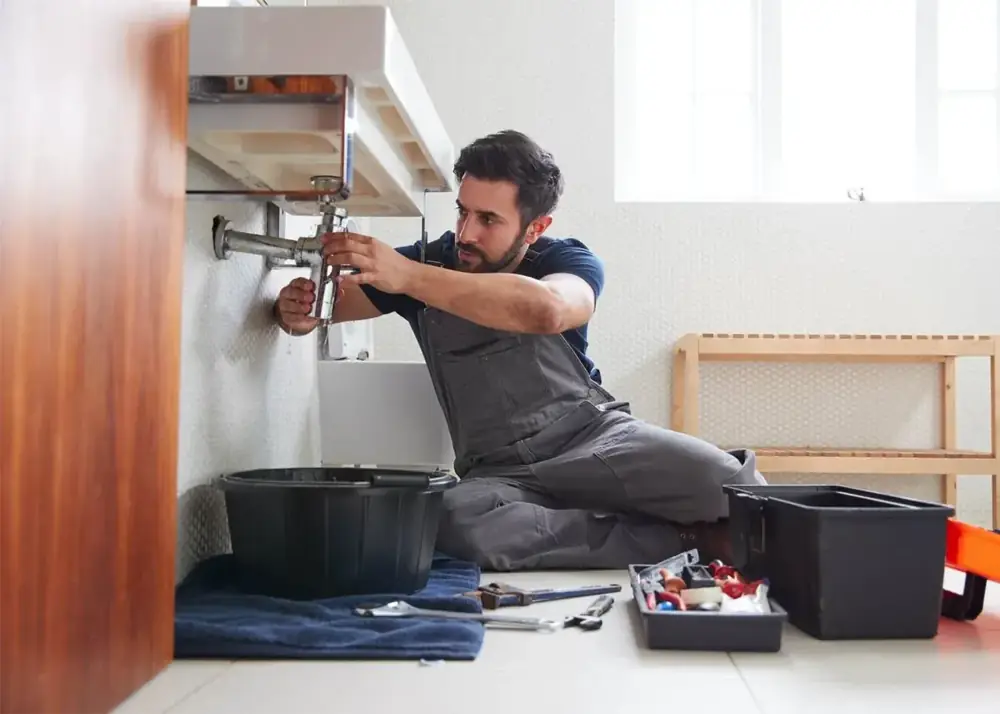 Plumber repairing supply line connections beneath a sink cabinet